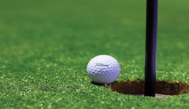 Golf ball next to hole