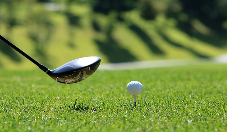 Golf club next to ball on tee