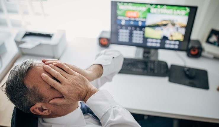 Man with head in hands in front of computer screen