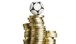 A pile of one pound coins with a football on top