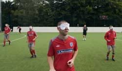 A Blind Football player stands on the field.