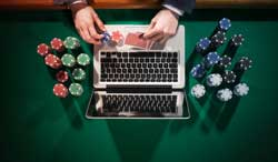 A hand places poker chips on a laptop.