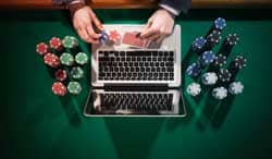 A hand places poker chips on a laptop.