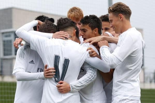 Real Madrid Castilla players huddle together after scoring a goal.
