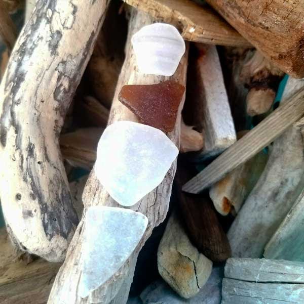 Piece of white smooth sea glass on driftwood.