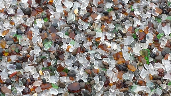 Smooth pieces of white, green and brown sea glass on the beach at Fort Bragg, California.