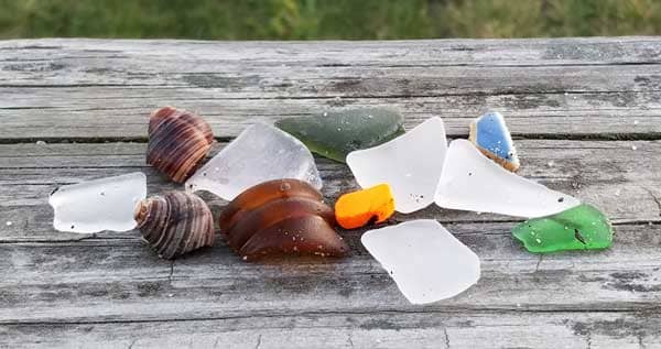 Smooth sea glass and sea pottery on a wood background.