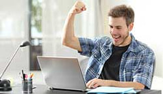 A man sat in front of his laptop and punching the air after making a football trading profit on Betfair.