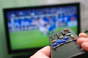 a TV remote being pointed at a television while a football match is being played.