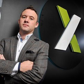CEO Mark Brosnan stands infront of the Xanadu Consultancy logo.