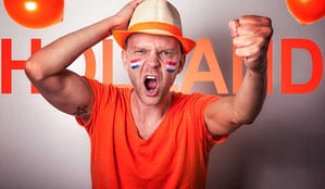 Dutch football fan wearing orange and cheering.