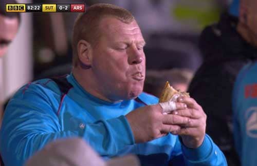 Wayne Shaw eats a pie during Sutton United's clash with Arsenal.