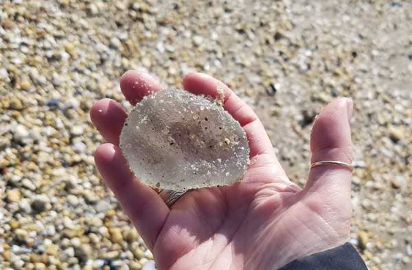 I'm holding in my hand a large piece of smooth sea glass on the beach in New Jersey.