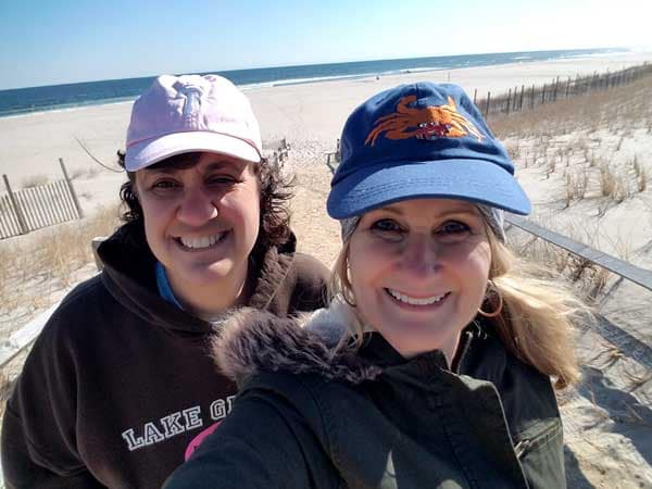 Two ladies on Long Beach Island looking for sea glass on the beach with sand and ocean in the back ground.