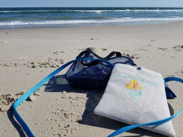 Sea glass hunting bags in the sand with ocean waves in back ground.