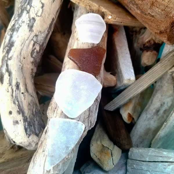 Piece of white smooth sea glass on driftwood.