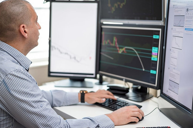 Man trading at computer with several screens