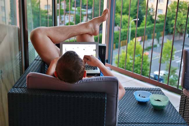 A naked man working from home with his laptop on his knees