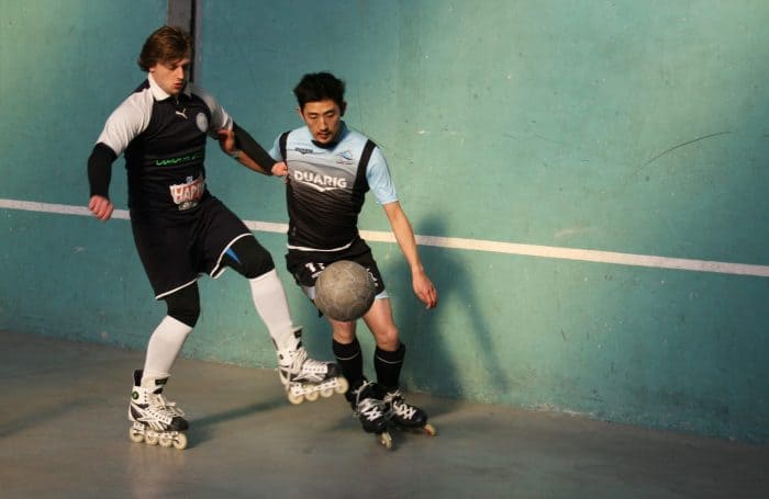 Two roller soccer players compete to win possession of the ball.