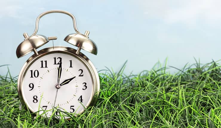 An alarm clock sitting on a grass football pitch.