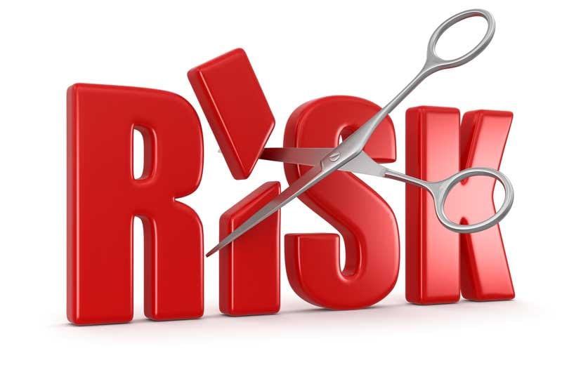 A pair of scissors cutting the word "RISK" in half.